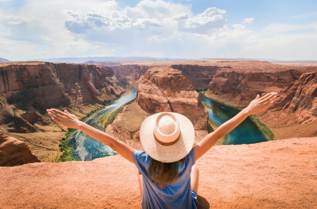 Woman enjoying a scenic view of Horseshoe Bend, Arizona on a sunny day.